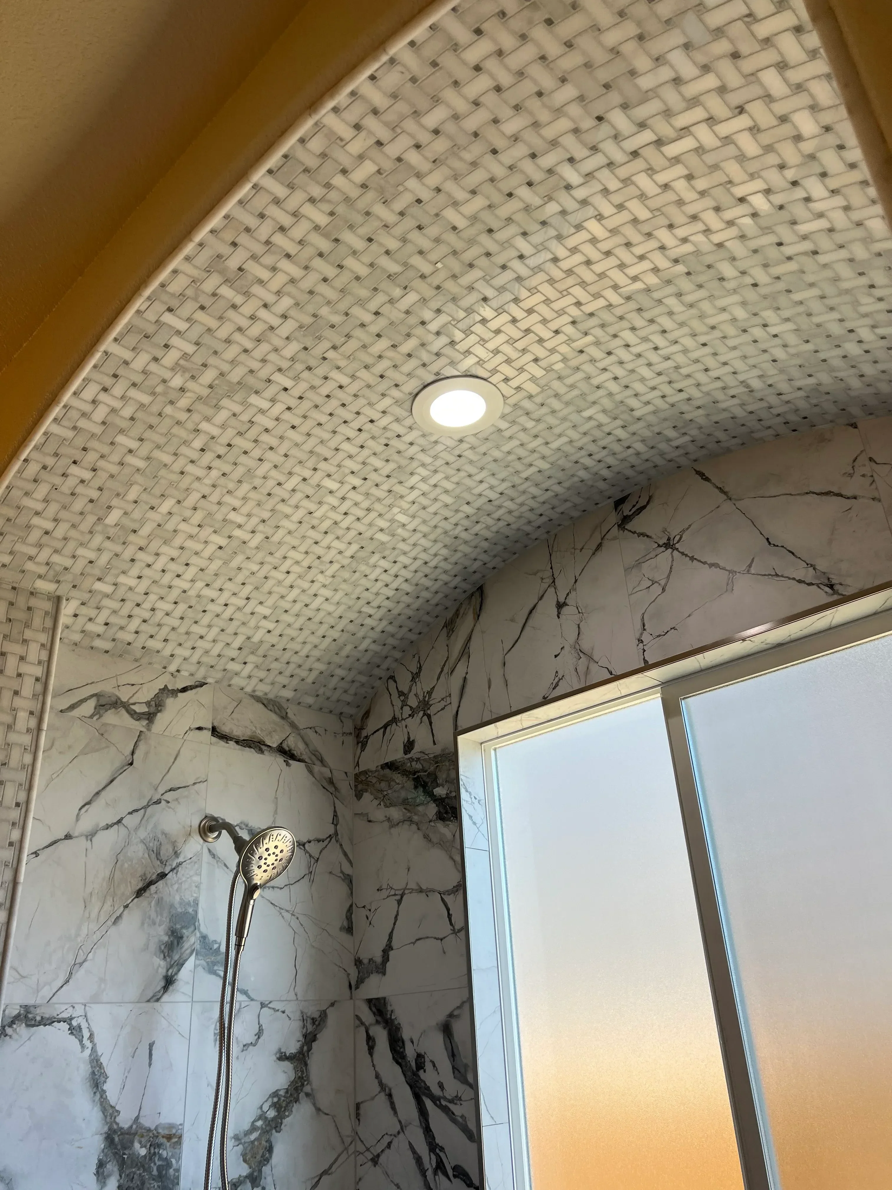 Marble tile shower walls with skylight and chrome showerhead fixture