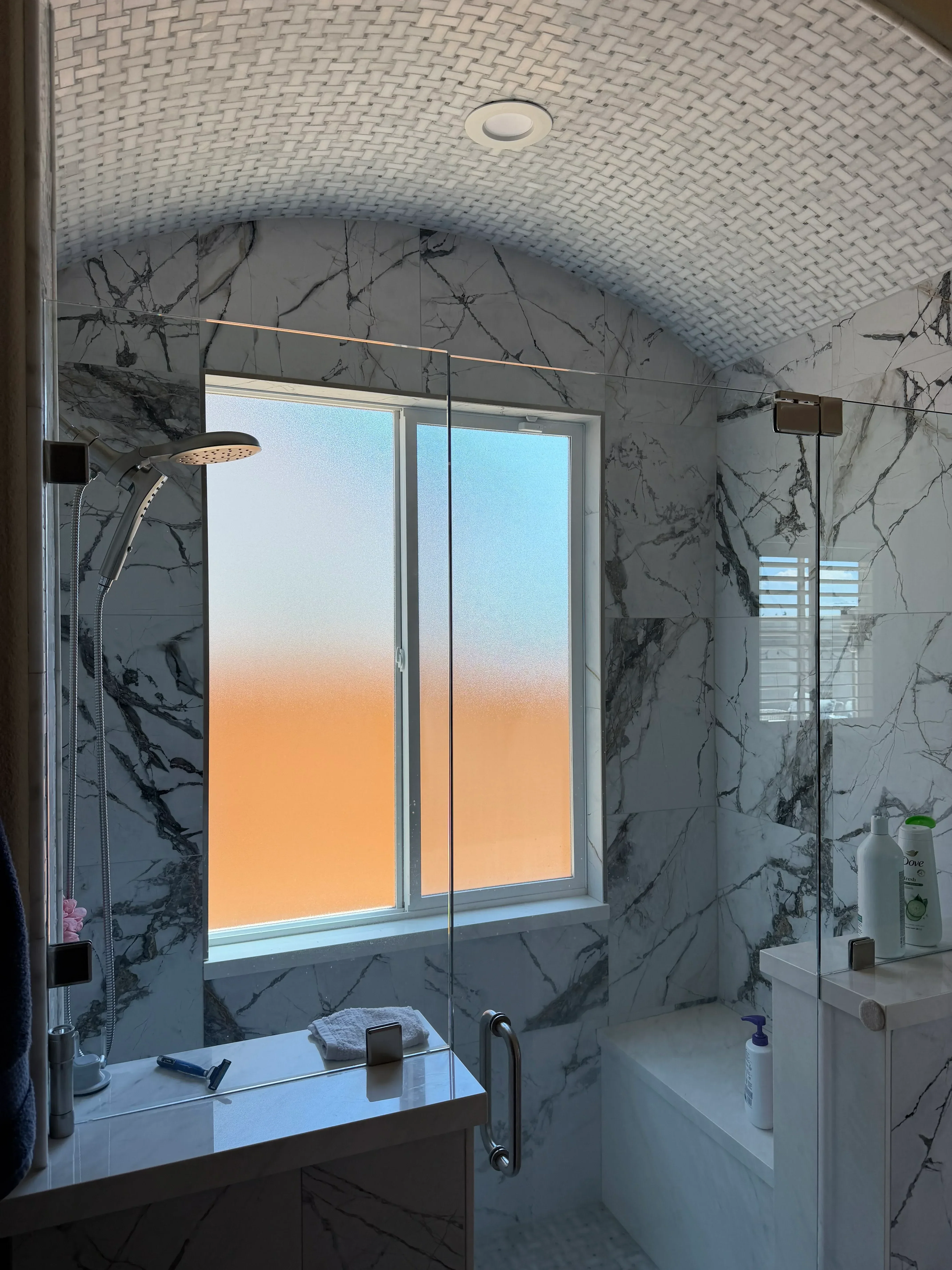 Marble tile bathroom with black veining, frameless glass shower, and subway tile accent wall