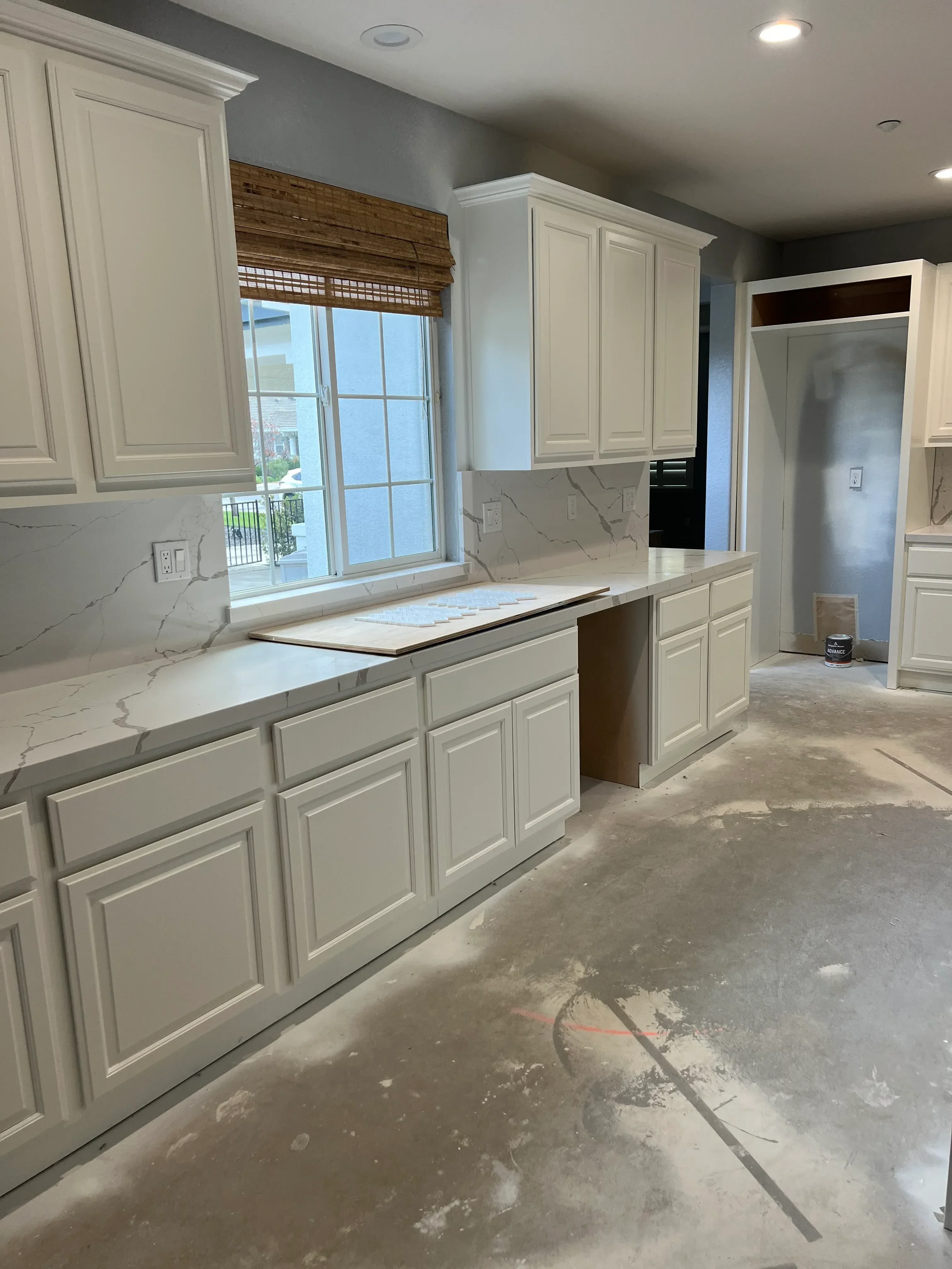 White shaker cabinetry, marble countertops, and electrical work in kitchen remodel