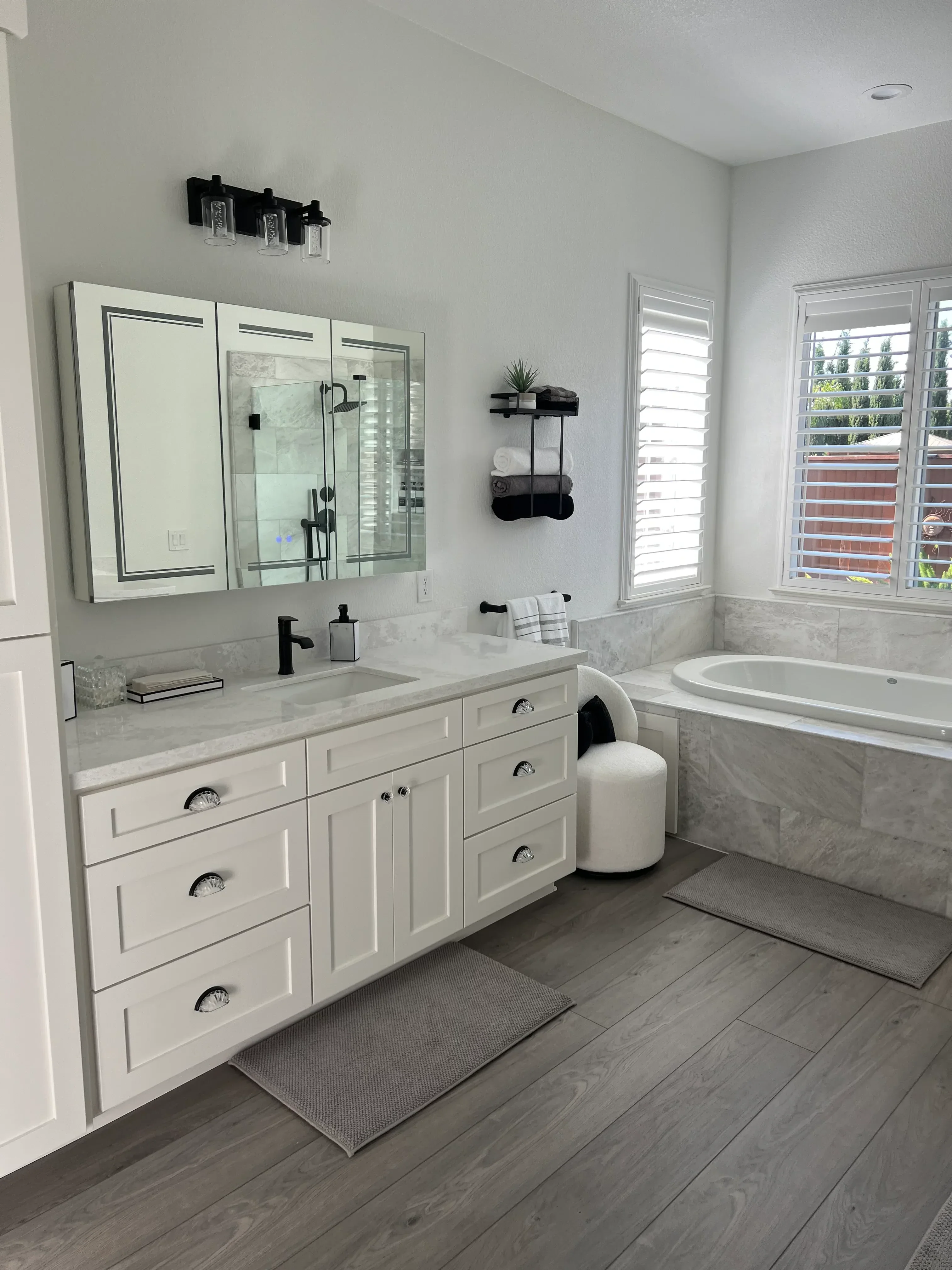 Gray tile walls, white vanity cabinets, frameless glass shower enclosure in modern bathroom
