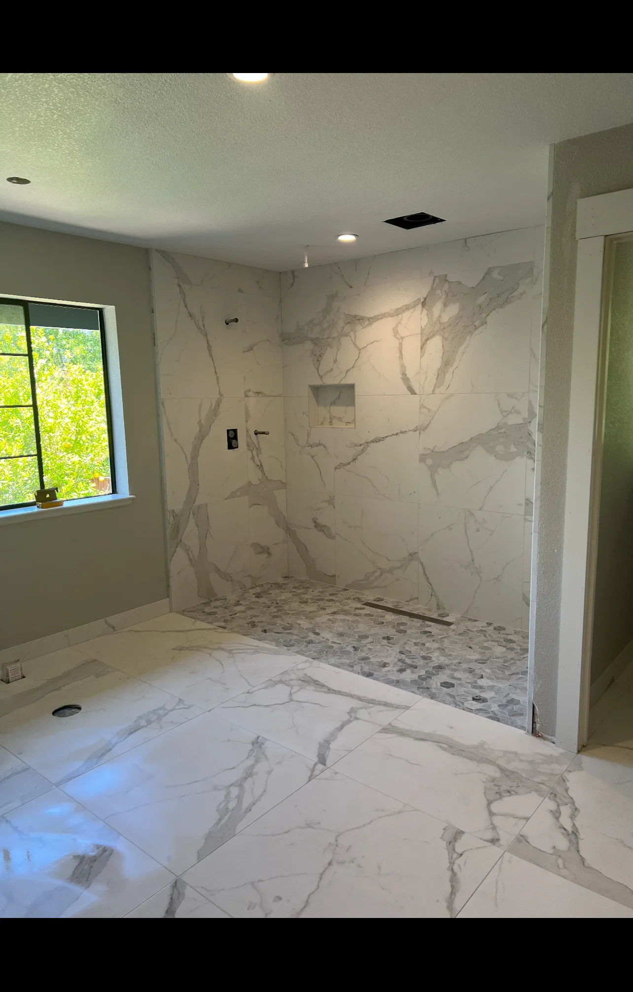 Marble tile bathroom with walk-in shower, pebble floor, and frameless glass enclosure
