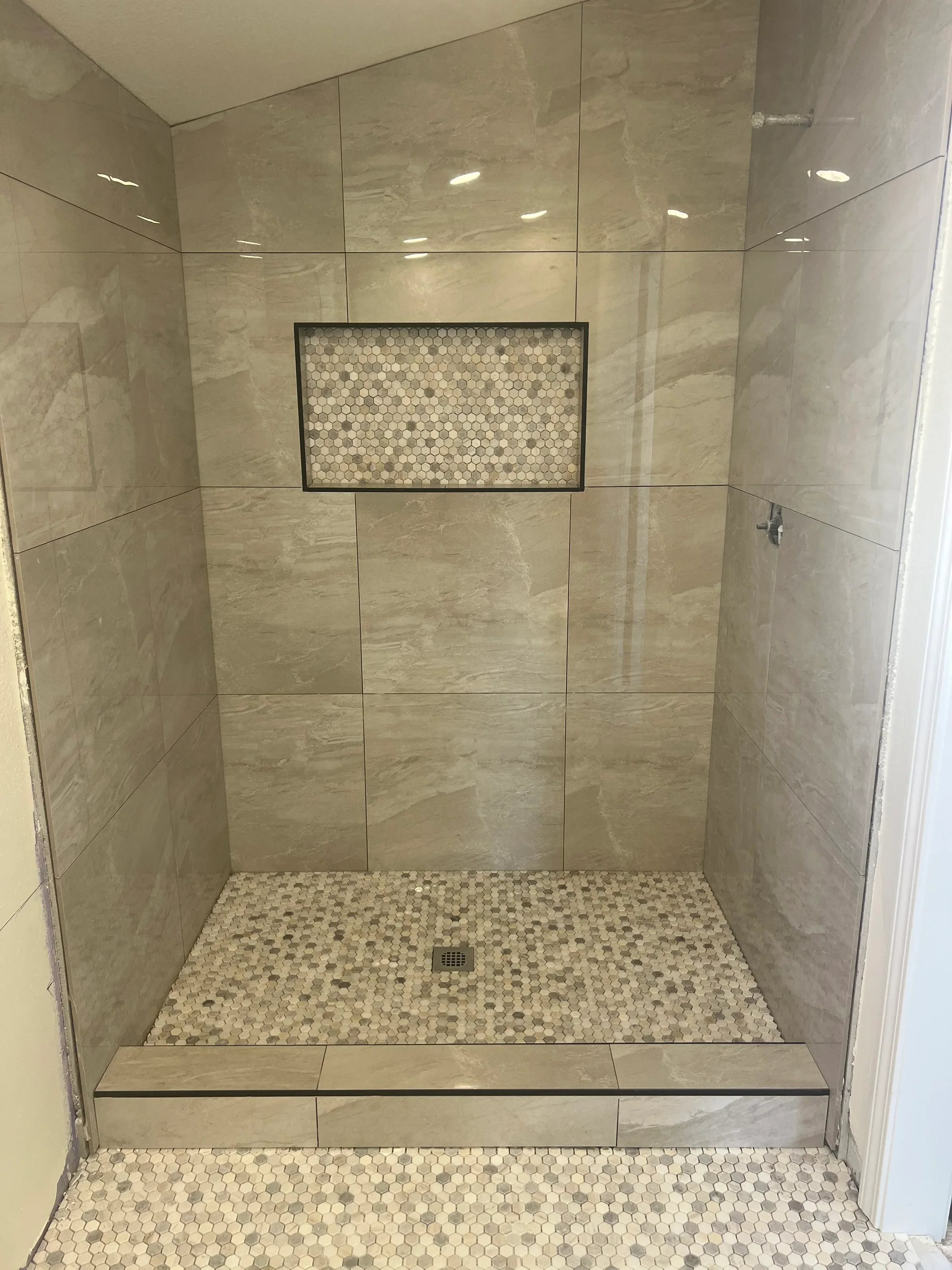 Walk-in shower with porcelain tile walls, penny tile accent, and frameless glass enclosure