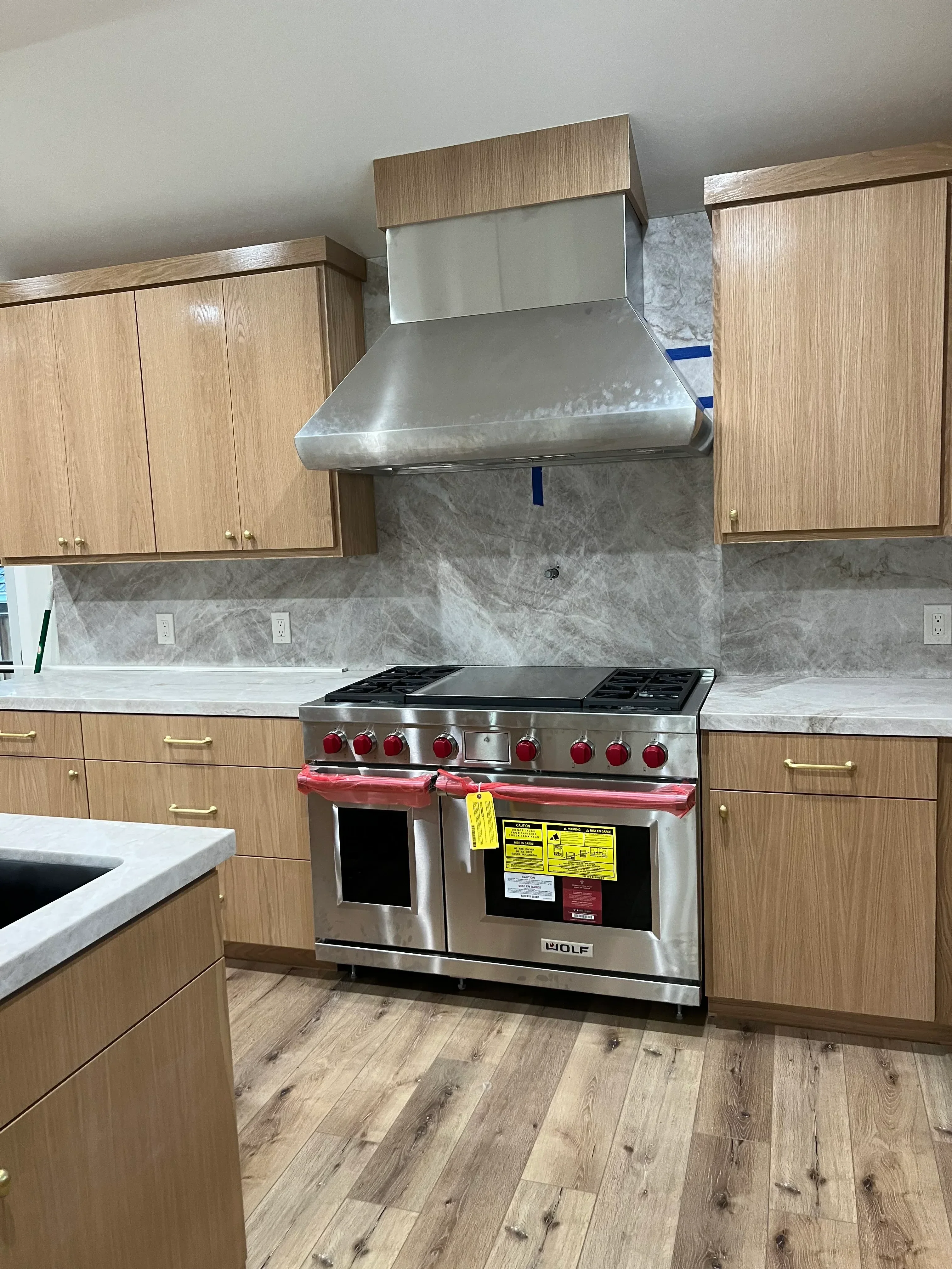 Kitchen remodel with wood cabinetry, marble backsplash, and stainless steel double wall oven