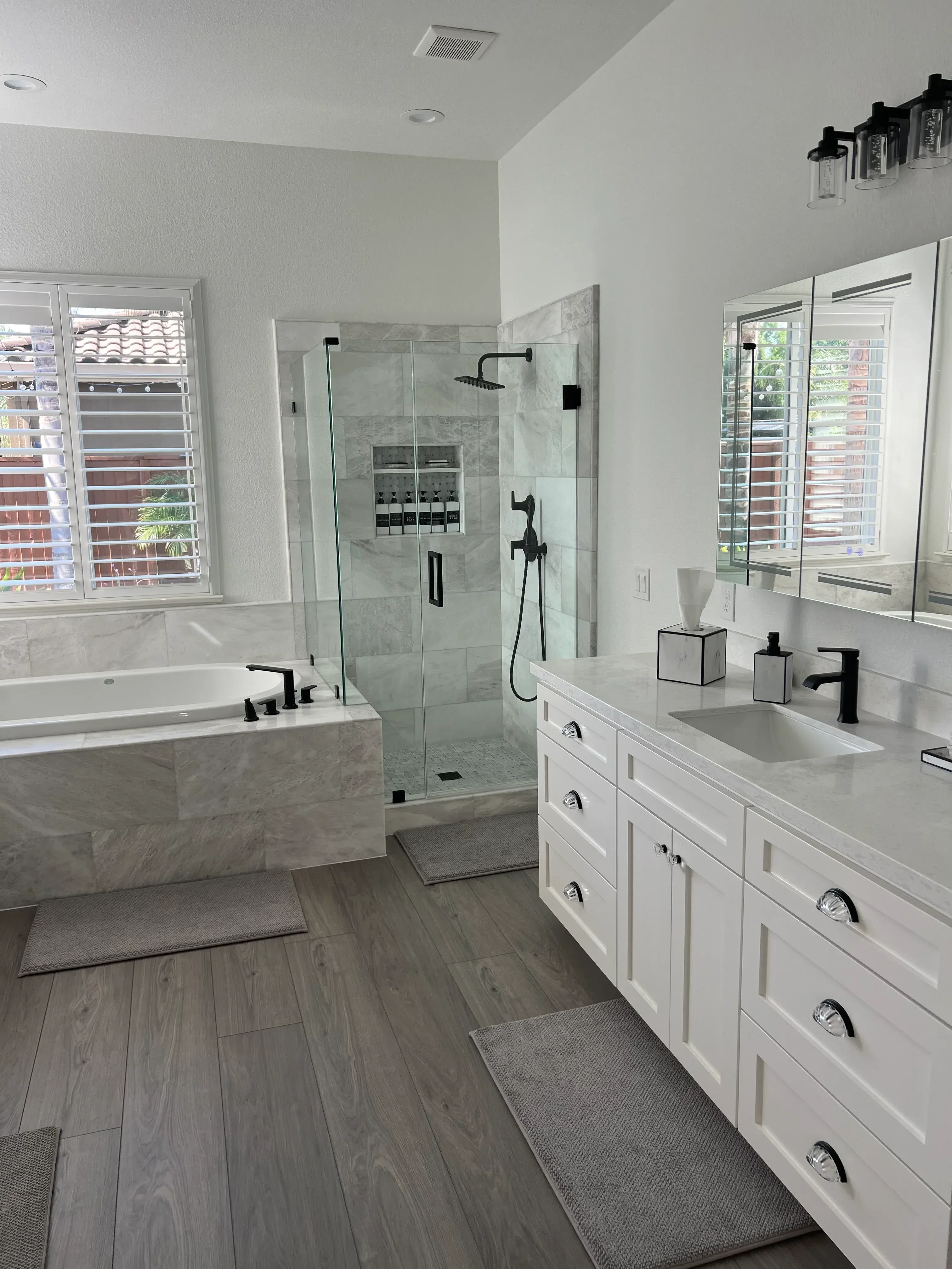 Gray tile shower with frameless glass door, coffered ceiling, and luxury vinyl plank flooring