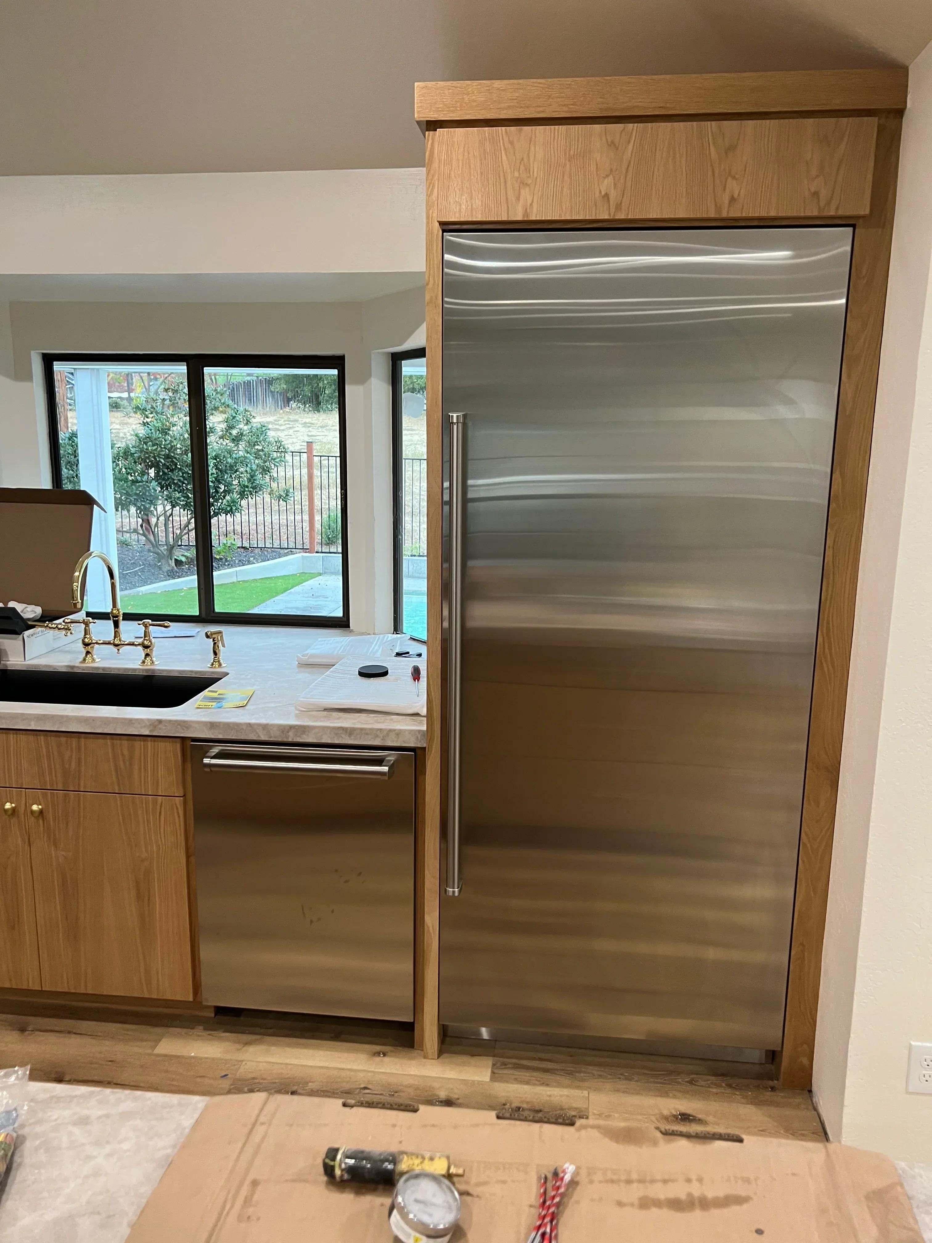 Oak kitchen cabinets with built-in TV mount and brass hardware, custom shelving installation