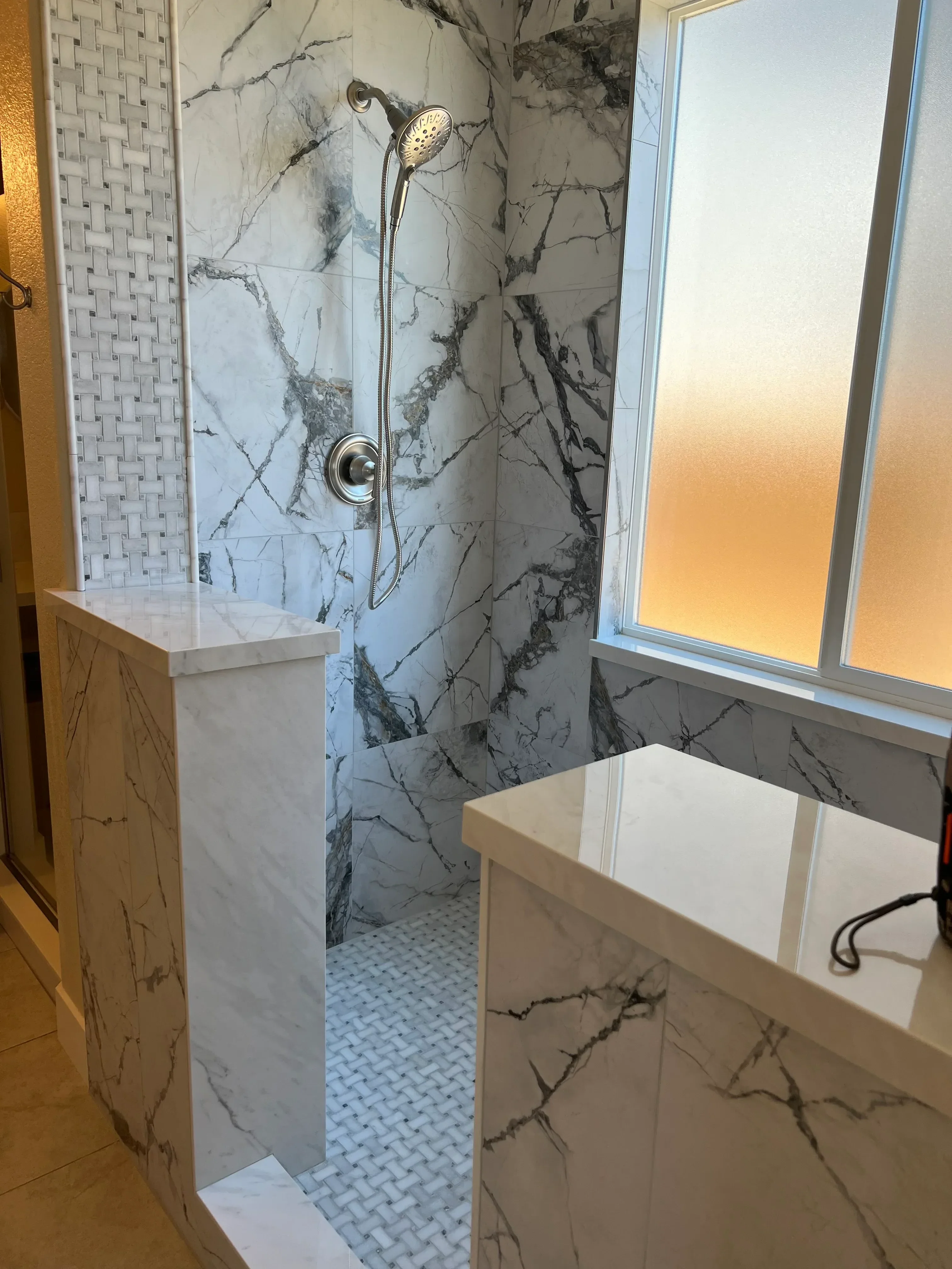 Marble tile bathroom with skylight, chrome fixtures, and mosaic floor tile