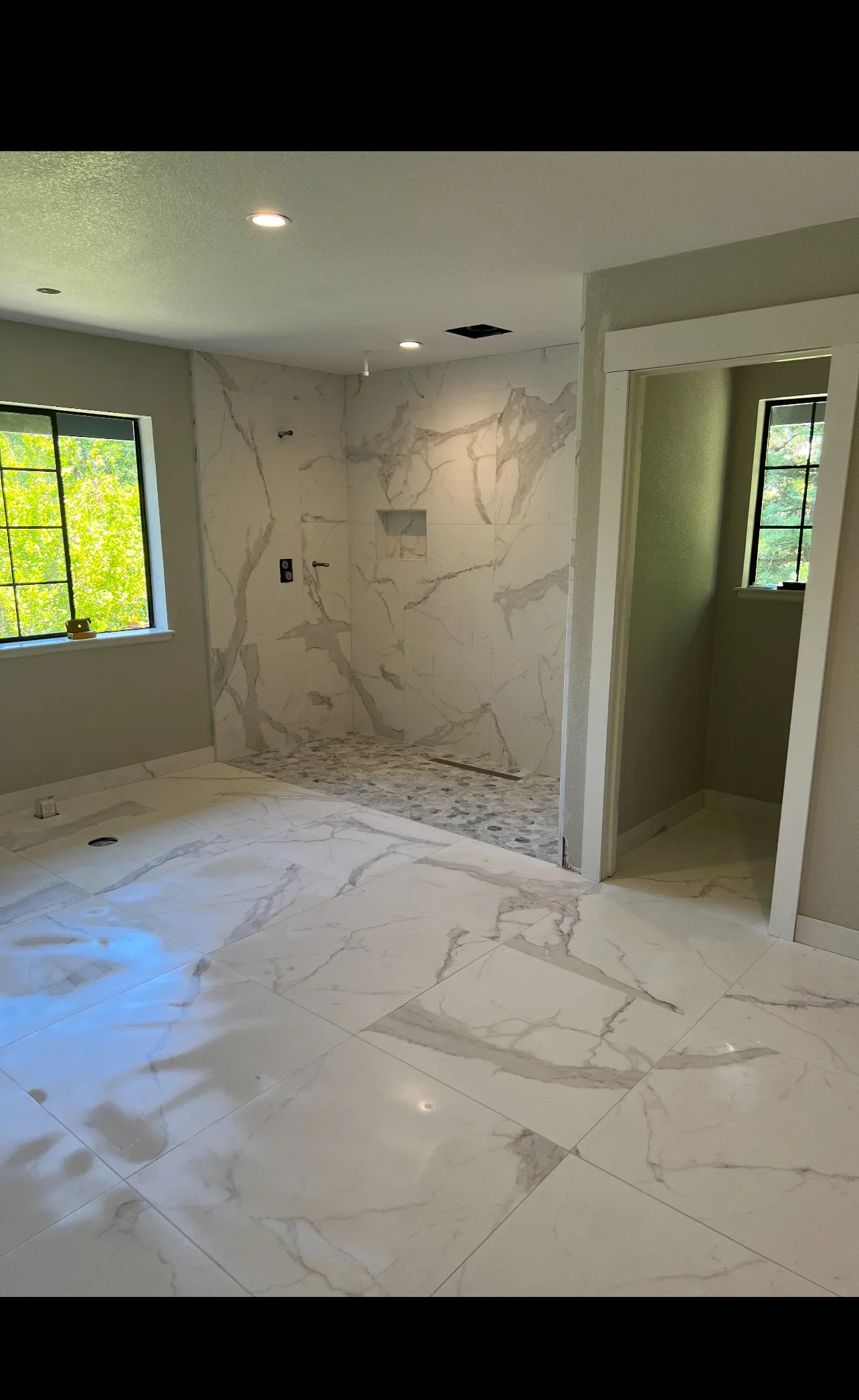 Marble tile bathroom with large-format flooring, marble shower walls, and recessed lighting