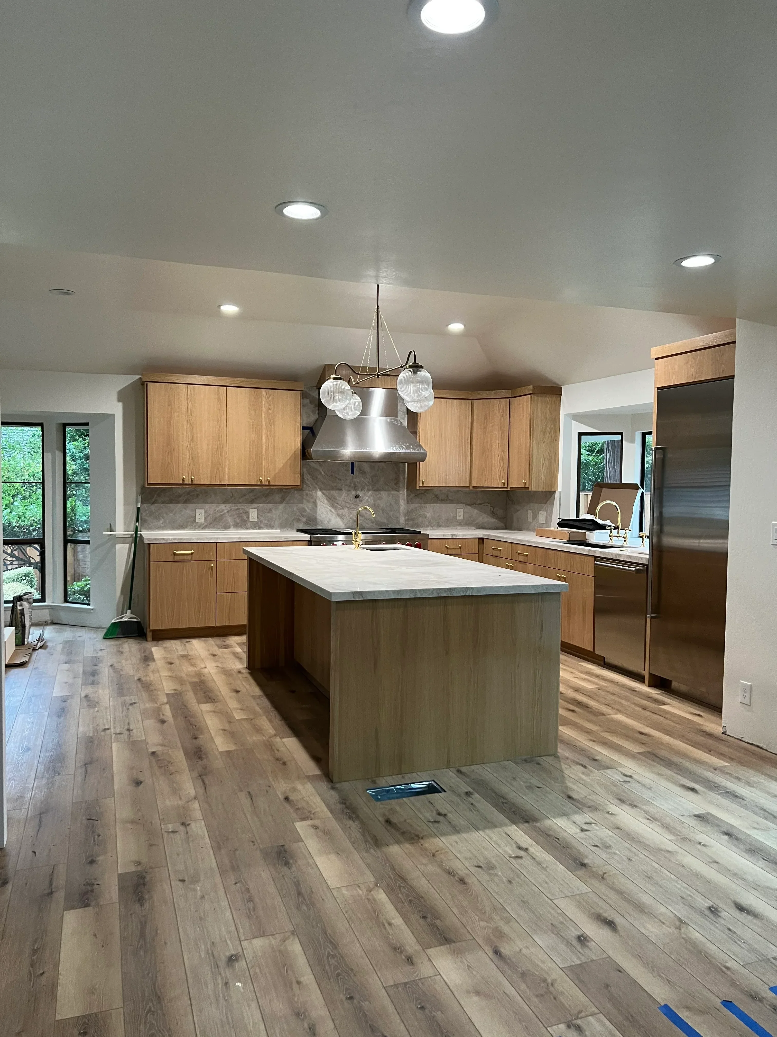 Kitchen with wood cabinets, gray tile backsplash, stainless steel range hood, and recessed lighting