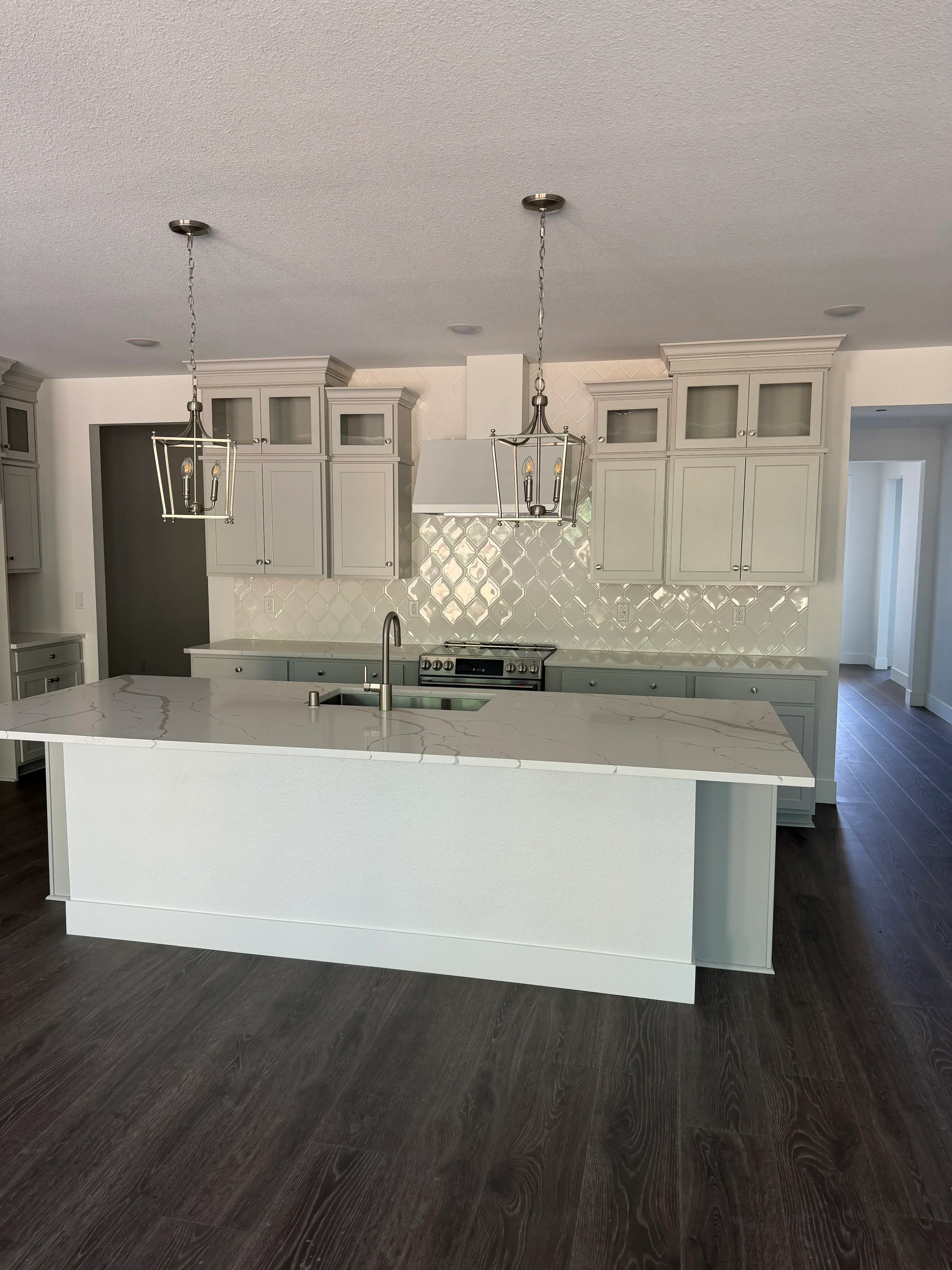 Cream shaker cabinets with marble diamond tile backsplash and dark wood flooring