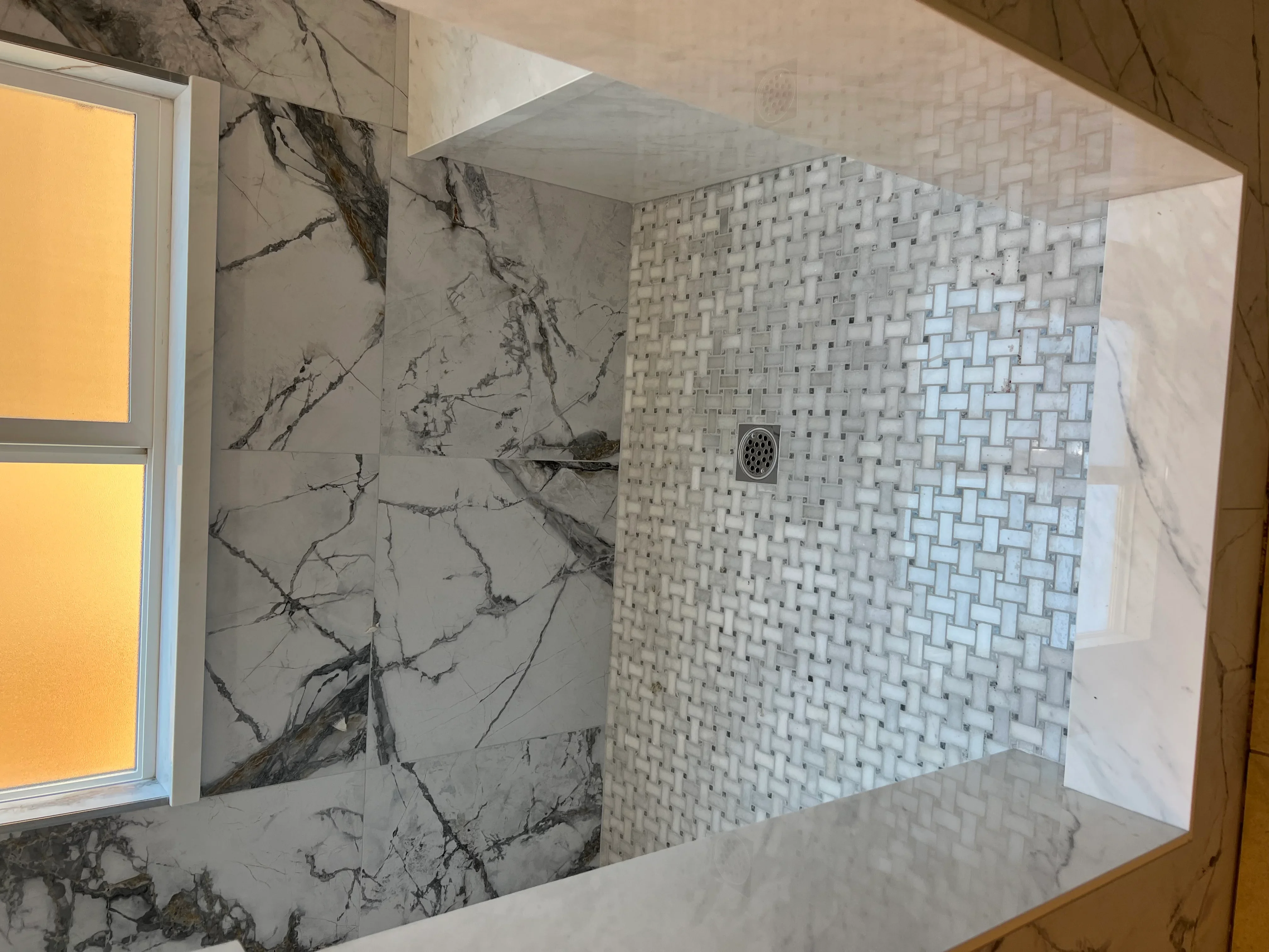 Marble and mosaic tile shower enclosure with geometric pattern accent wall