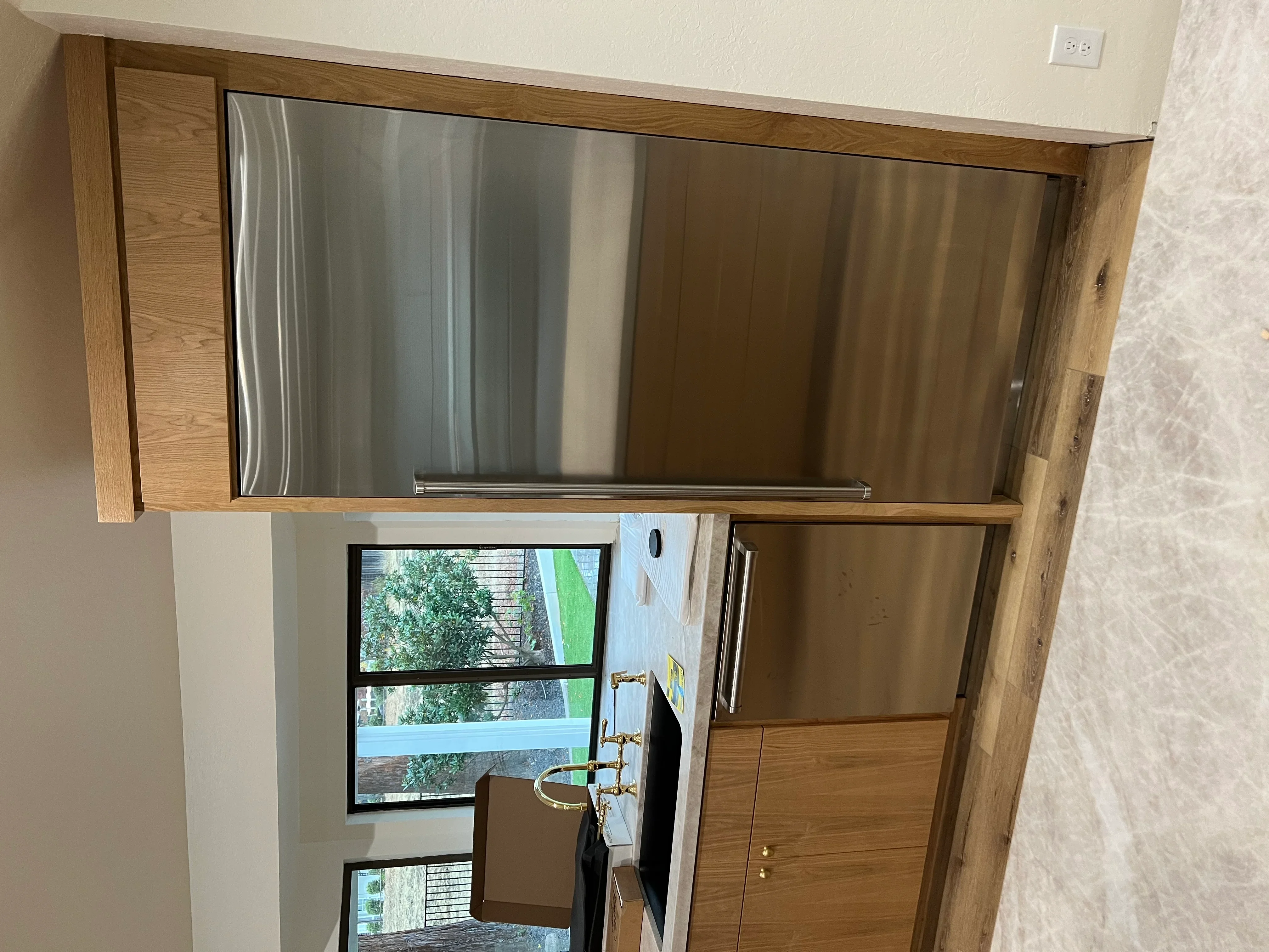 Oak cabinetry with mounted flat-screen TV and lower storage cabinet with brass hardware