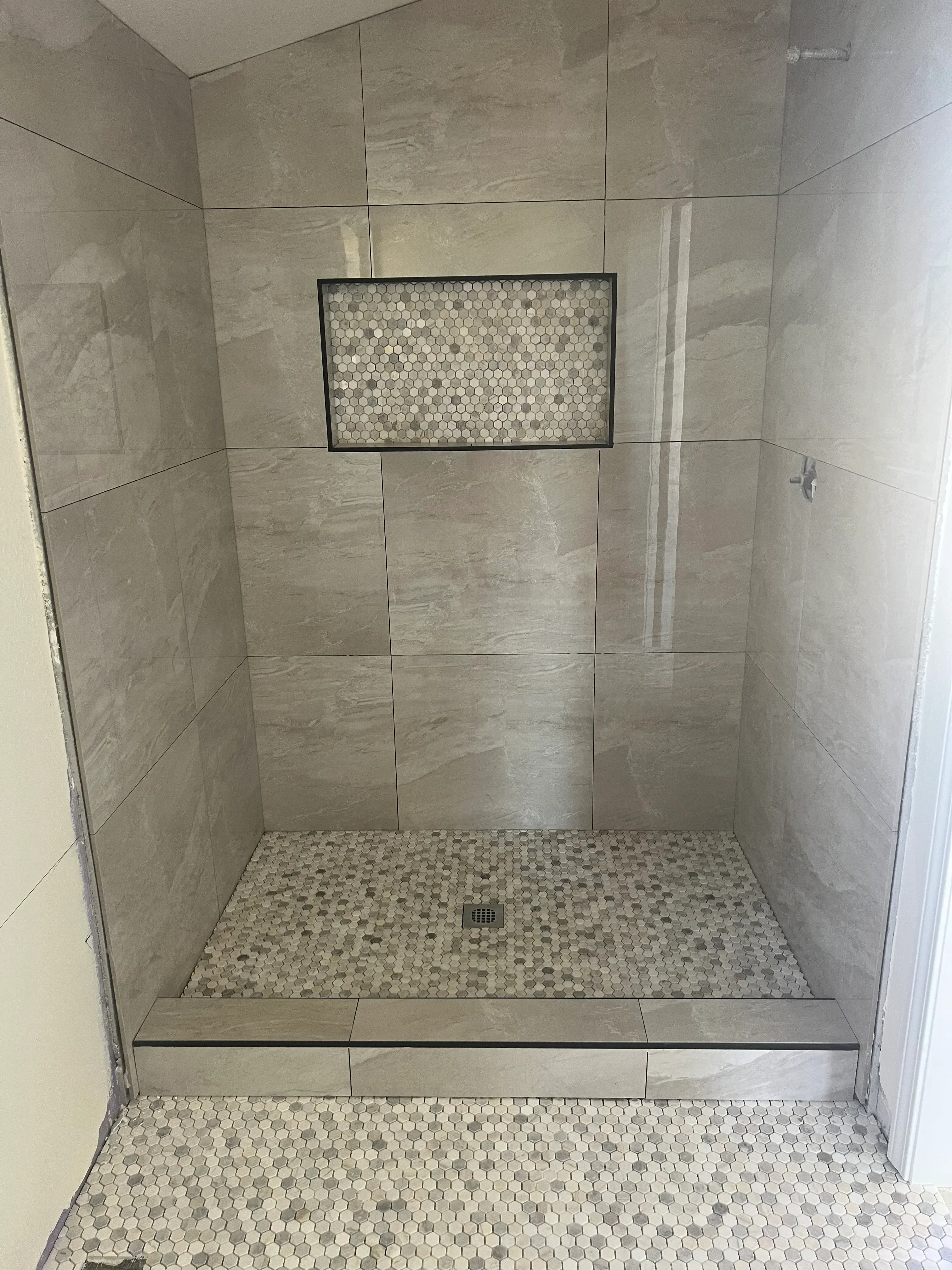 Walk-in shower with porcelain tiles, penny tile accent wall, and frameless glass enclosure