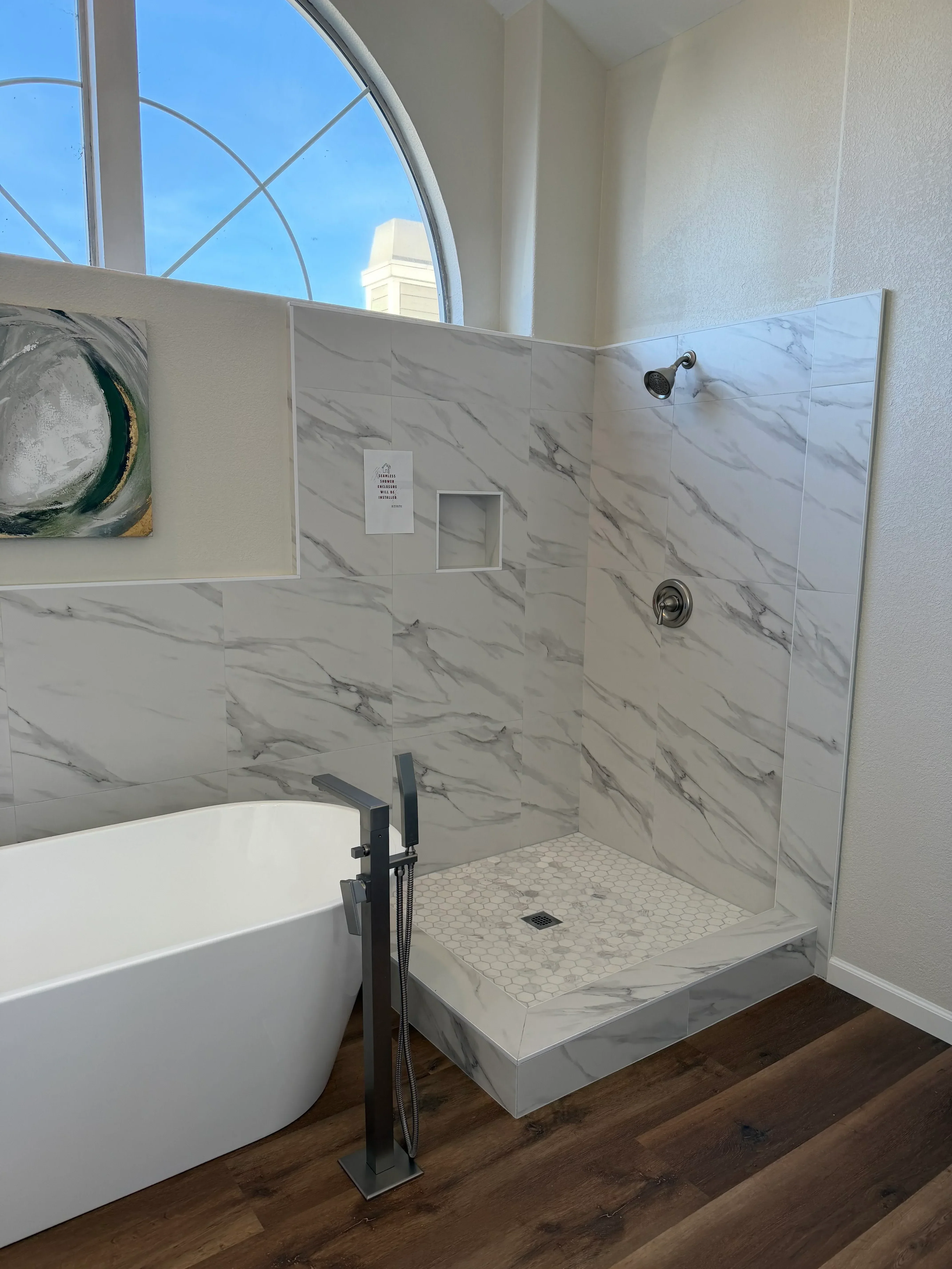 Marble tile shower with gray veining, recessed niche, and hexagonal accent tile